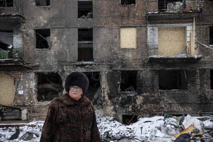 Een vrouw voor een beschadigd woongebouw als gevolg van de oorlog tussen Rusland en Oekraïne. Foto: ANP / Metin Aktas / Anadolu Agency
